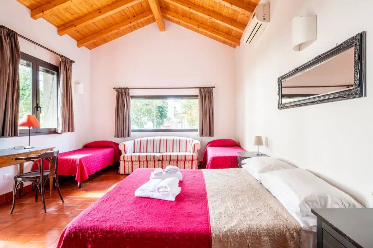 A bedroom with a large bed, two single beds, a desk, and a chair.