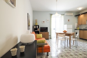 Un espacio habitable compacto con sofá, mesa de comedor y kitchenette.