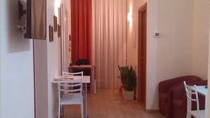 Ein modernes Wohnzimmer mit Essbereich, einem roten Sofa und einem Blumentopf.