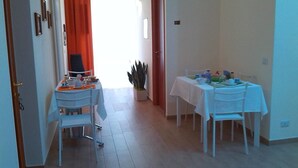 Ein Essbereich mit einem für zwei Personen gedeckten Tisch, einem weißen Stuhl und einer Pflanze in der Ecke.