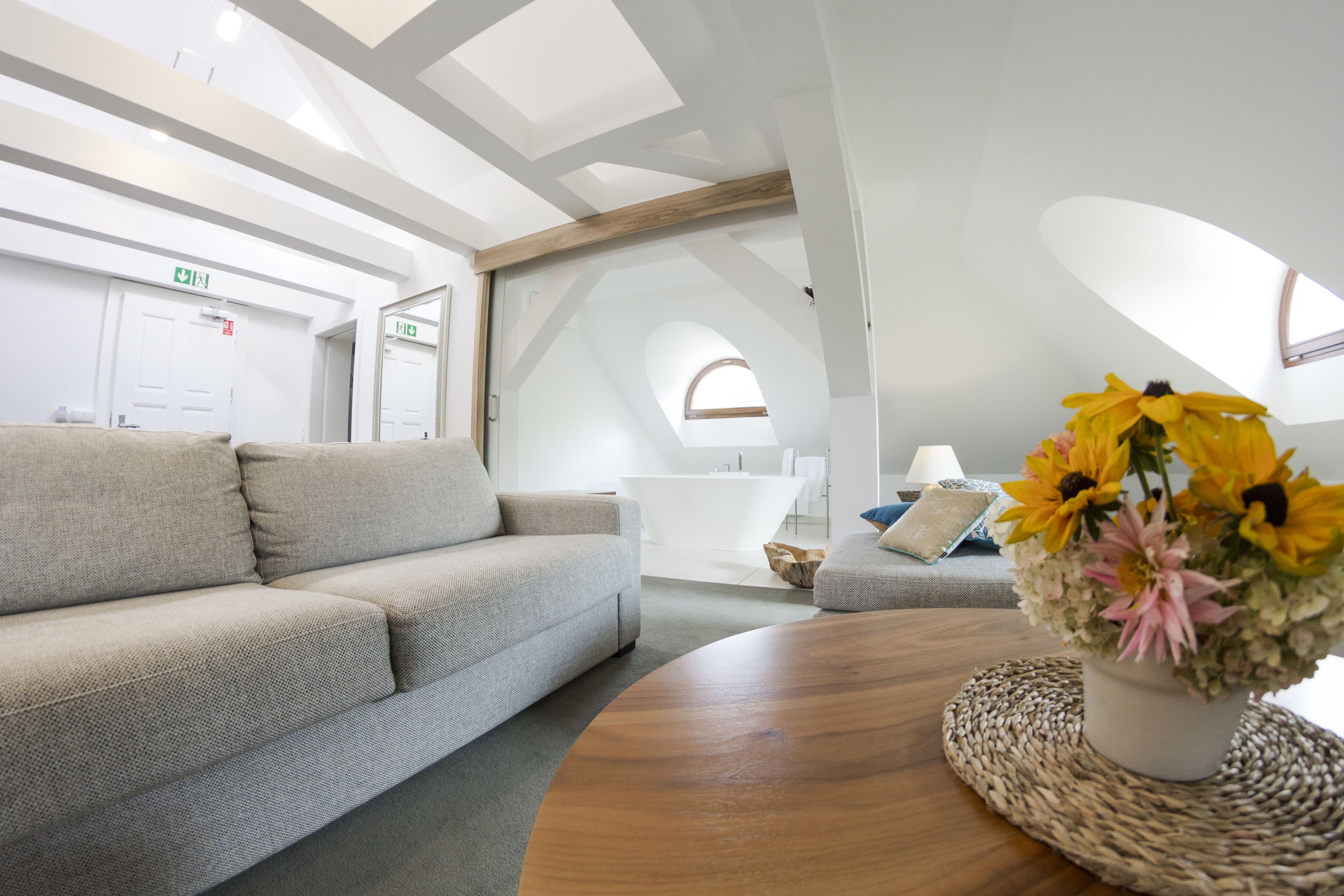 Ein modernes Interieur mit einer Couch, einem runden Holztisch mit geflochtener Tischunterlage und einer Blumenvase.