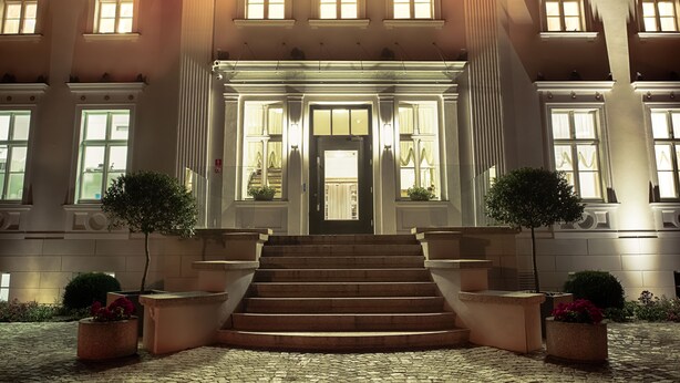 A grand building with a symmetrical facade, large windows, and a central entrance with steps leading up to it. - Jakubus (Wilków)