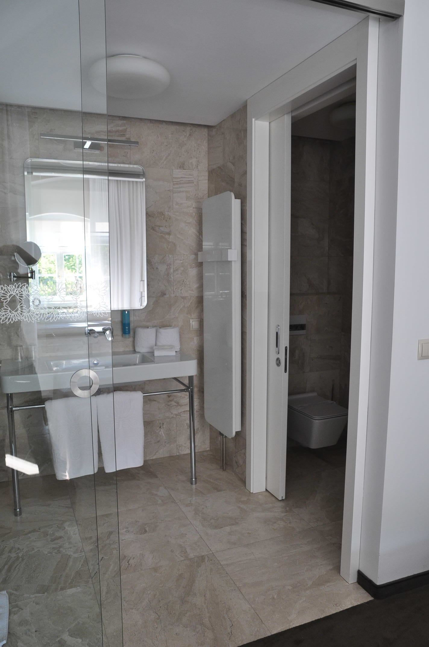 A modern bathroom with a glass partition, a white sink, a mirror, and a shower area.
