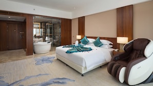 Habitación de hotel con una cama grande, una silla de masajes, una bañera y un área de ducha con paredes de vidrio.