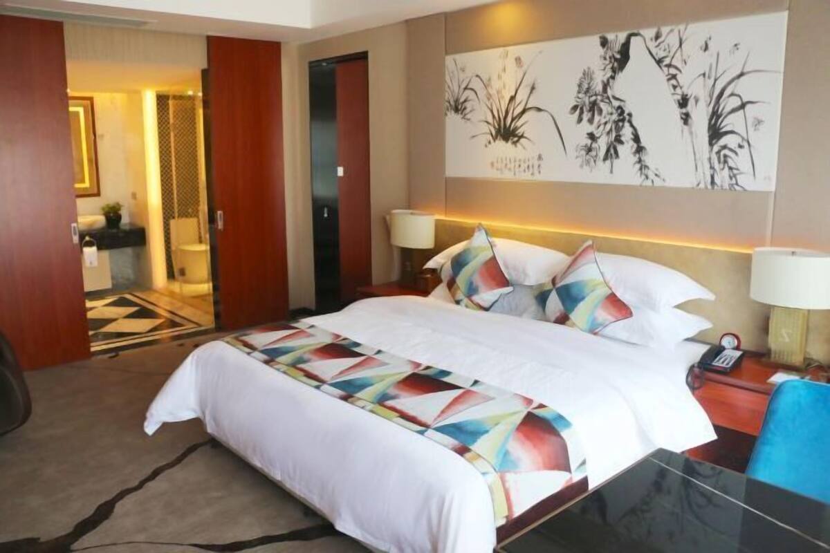 Una habitación de hotel con una cama, mesitas de noche, un escritorio y una silla.