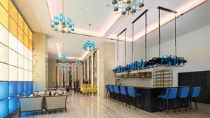 Un área de bar moderna con sillas azules, una barra y varias lámparas colgantes.