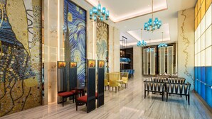 Un moderno vestíbulo de hotel con un amplio mural abstracto, zonas de estar e iluminación contemporánea.