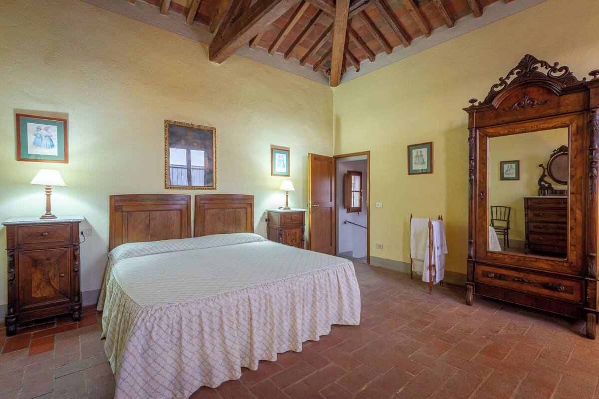 Quarto com cama grande, móveis de madeira e espelho.