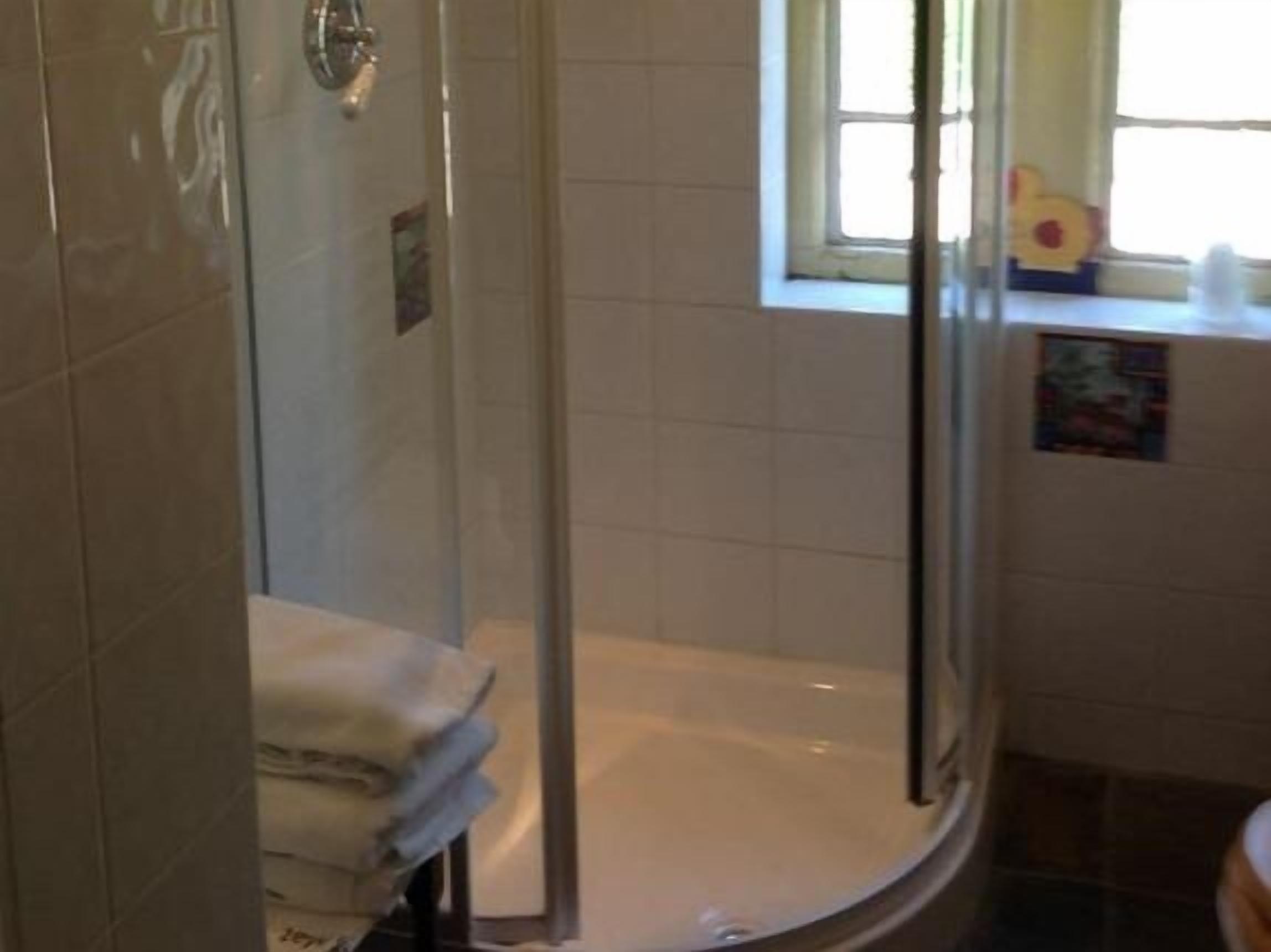 Un baño con ducha envuelta en vidrio, bañera y ventana con vistas.