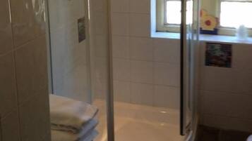 Un baño con ducha envuelta en vidrio, bañera y ventana con vistas.