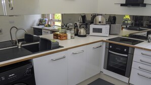 Una cocina moderna equipada con lavavajillas, horno, microondas, hervidor y un lavabo.
