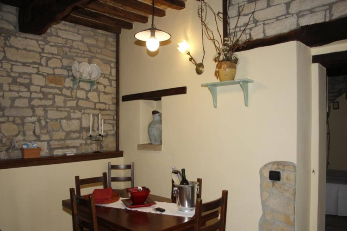 Ein Essbereich mit Steinwand, Holzkästen, einem Tisch mit roter Platzset, einer Vase und einer Pendelleuchte.