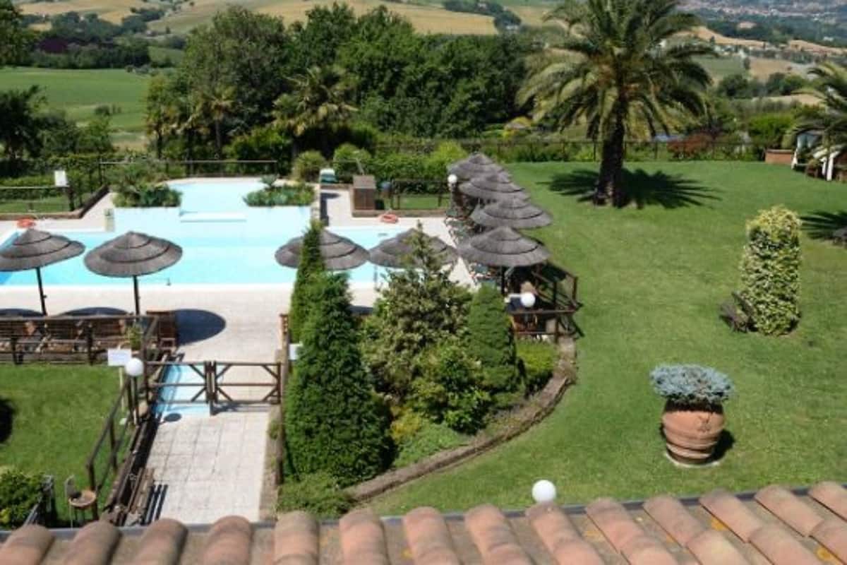 Ein Poolbereich mit Sonnenschirmen, einer Terrasse und Blick auf die umliegende Landschaft.