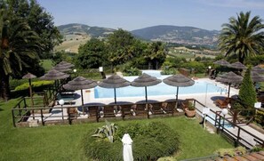A pool area with umbrellas, lounge chairs, and a view of the surrounding landscape.