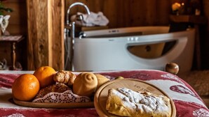 Una habitación acogedora con detalles de madera, una bañera y una mesa con pasteles y naranjas.
