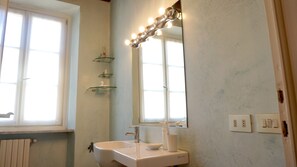 Un baño con lavamanos, espejo y repisas.