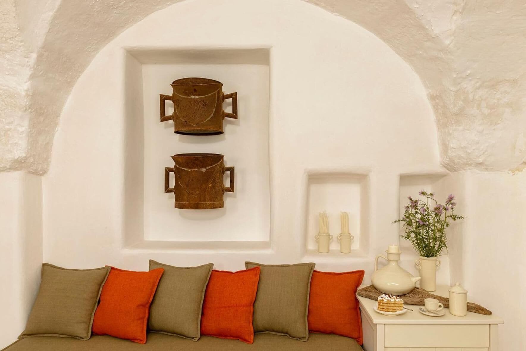 A cozy room with a bed, a small table with a vase of flowers, and two wall-mounted containers.