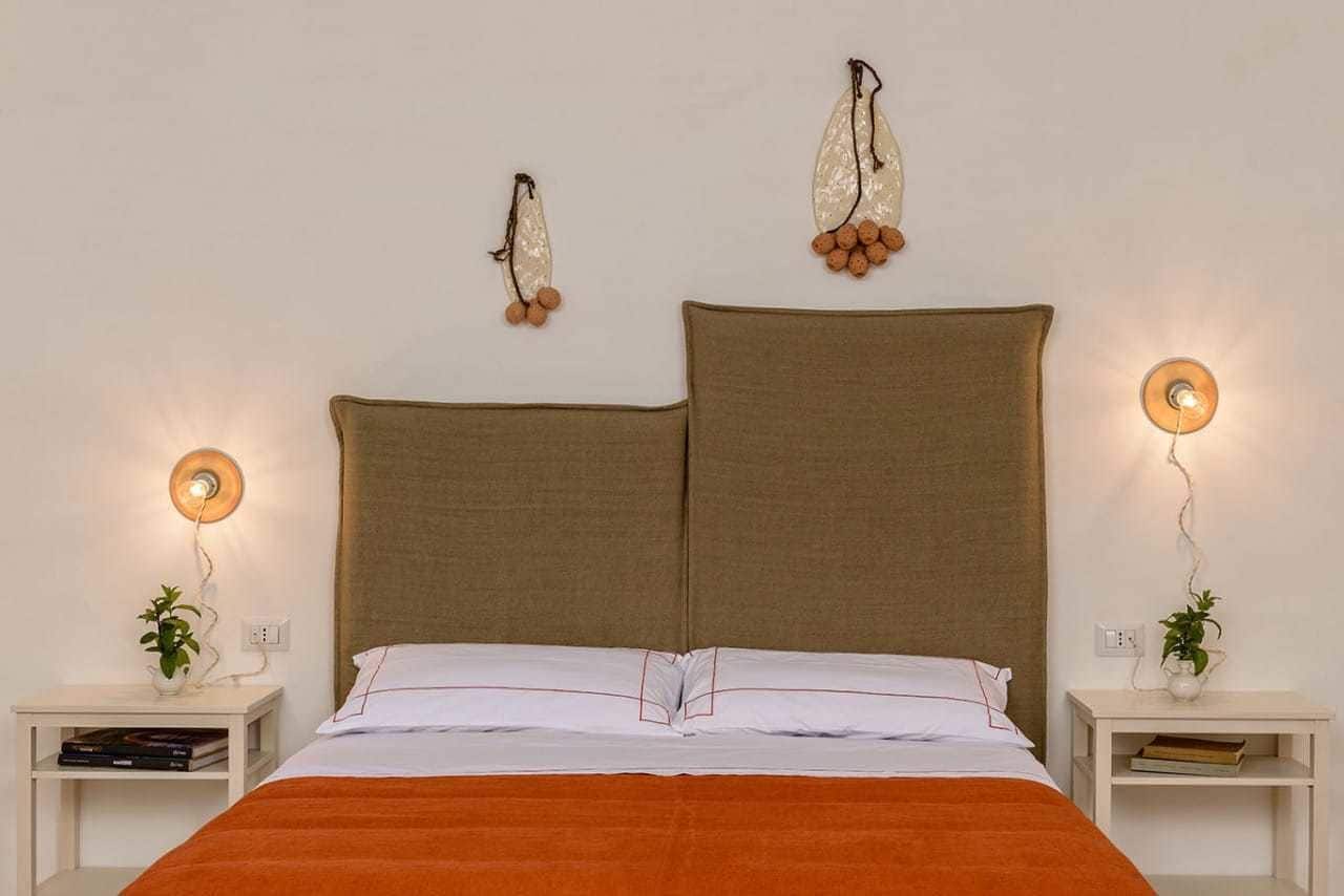 A bedroom with a large bed, two bedside tables with lamps, and wall-mounted decorative items.