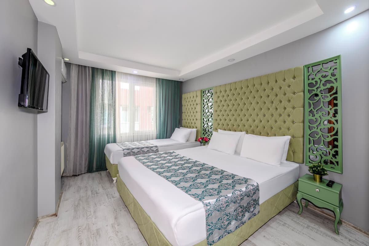 A hotel room with a large bed, a green nightstand, a TV mounted on the wall, and a decorative panel on the wall.