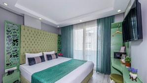 A modern hotel room with a large bed, green accents, a flat-screen TV, and a small table with a plant. - Green Garden Hotel (Istanbul)