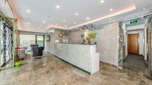A hotel reception area with a marble floor, a reception desk, a bicycle, and a world map on the wall. - Green Garden Hotel (Istanbul)