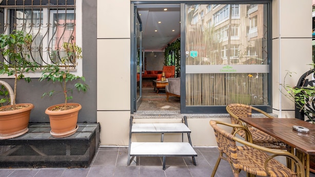 An outdoor seating area with wicker furniture, terracotta planters, and a glass door leading to an interior space. - Green Garden Hotel (Istanbul)
