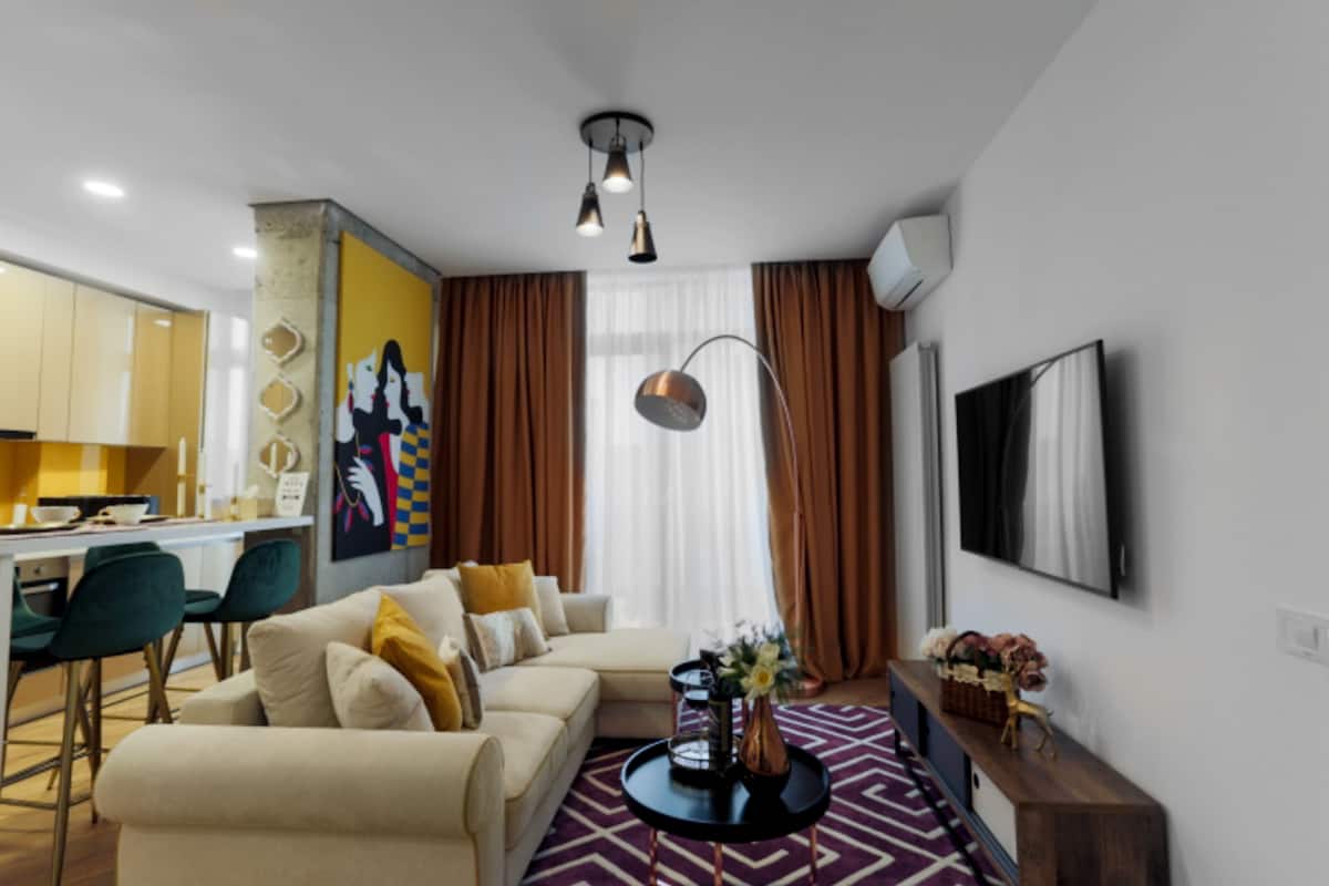 A modern living room with a sofa, a coffee table, and a TV mounted on the wall.