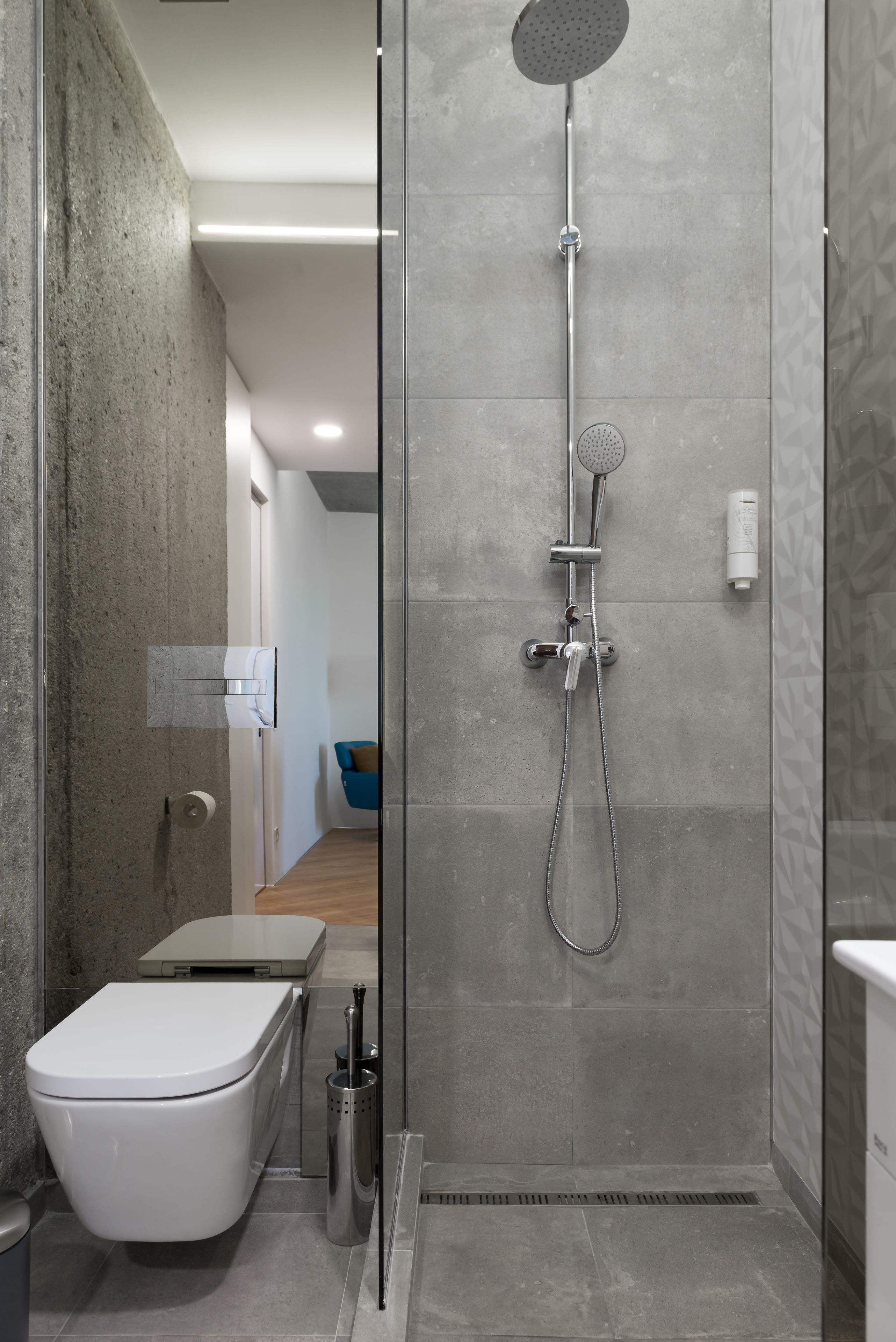 A modern bathroom with a glass-enclosed shower, a toilet, and a bidet.
