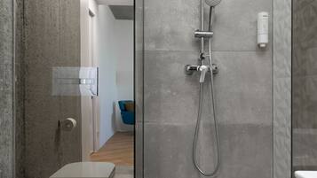 A modern bathroom with a glass-enclosed shower, a toilet, and a bidet.
