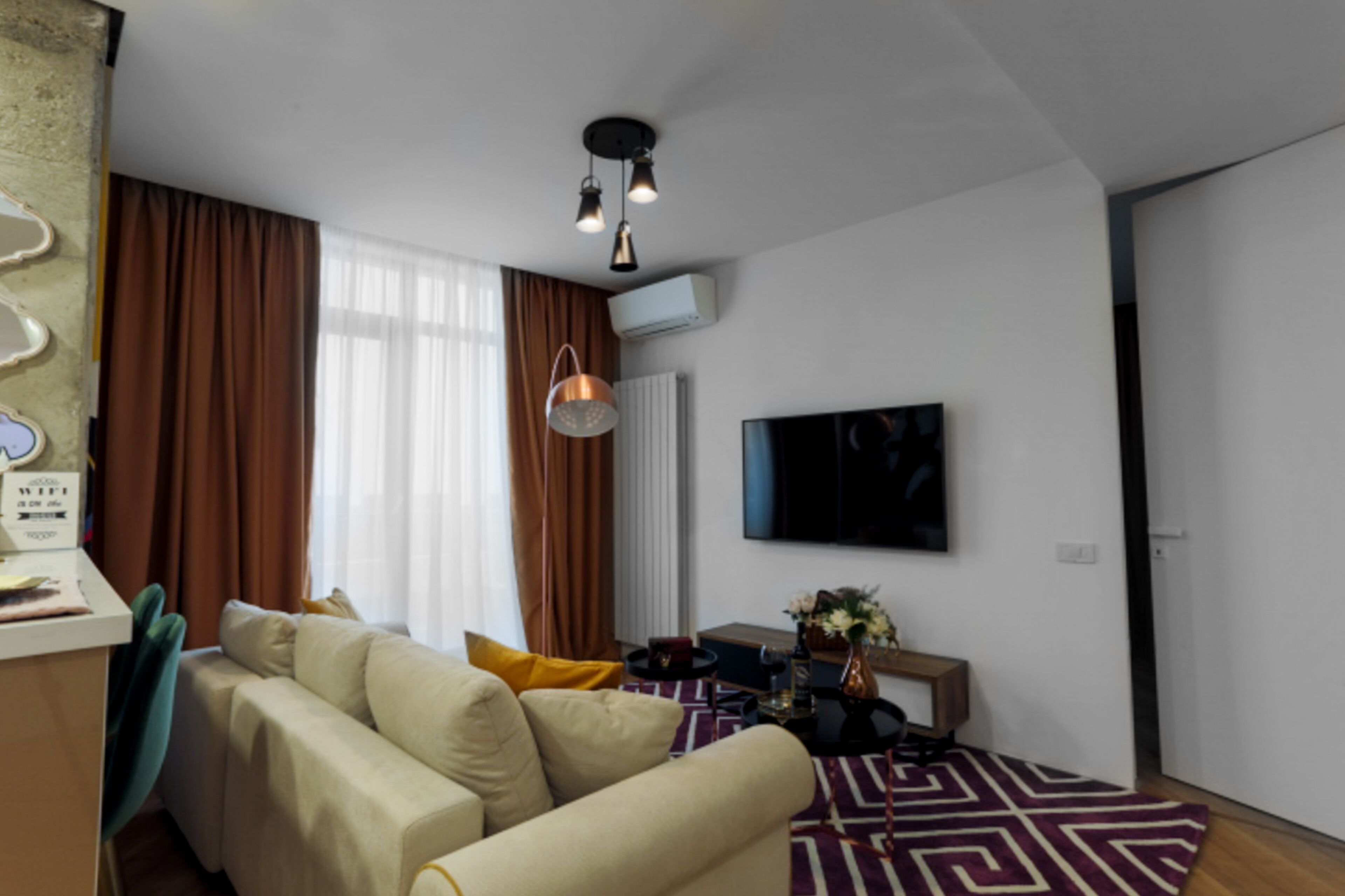 A modern living room with a sofa, a coffee table, and a flat-screen TV mounted on the wall.