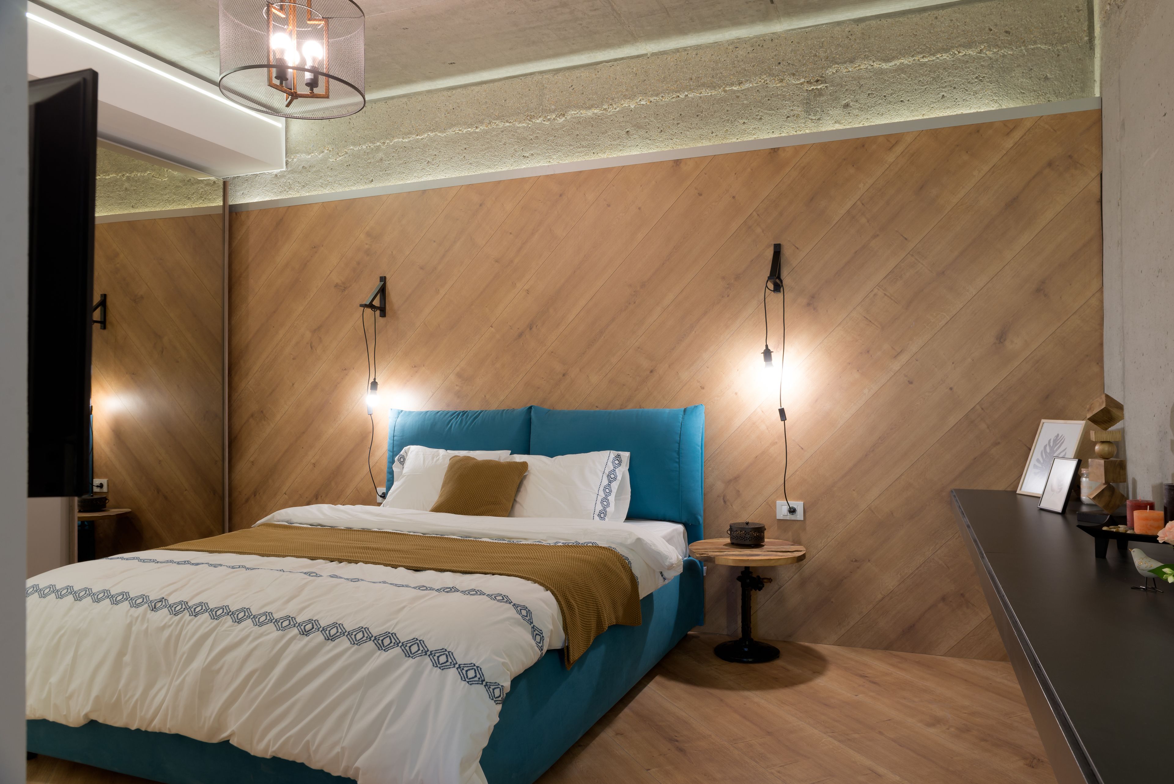 Een moderne slaapkamer met een groot bed, houten wanden en twee wandlampen.