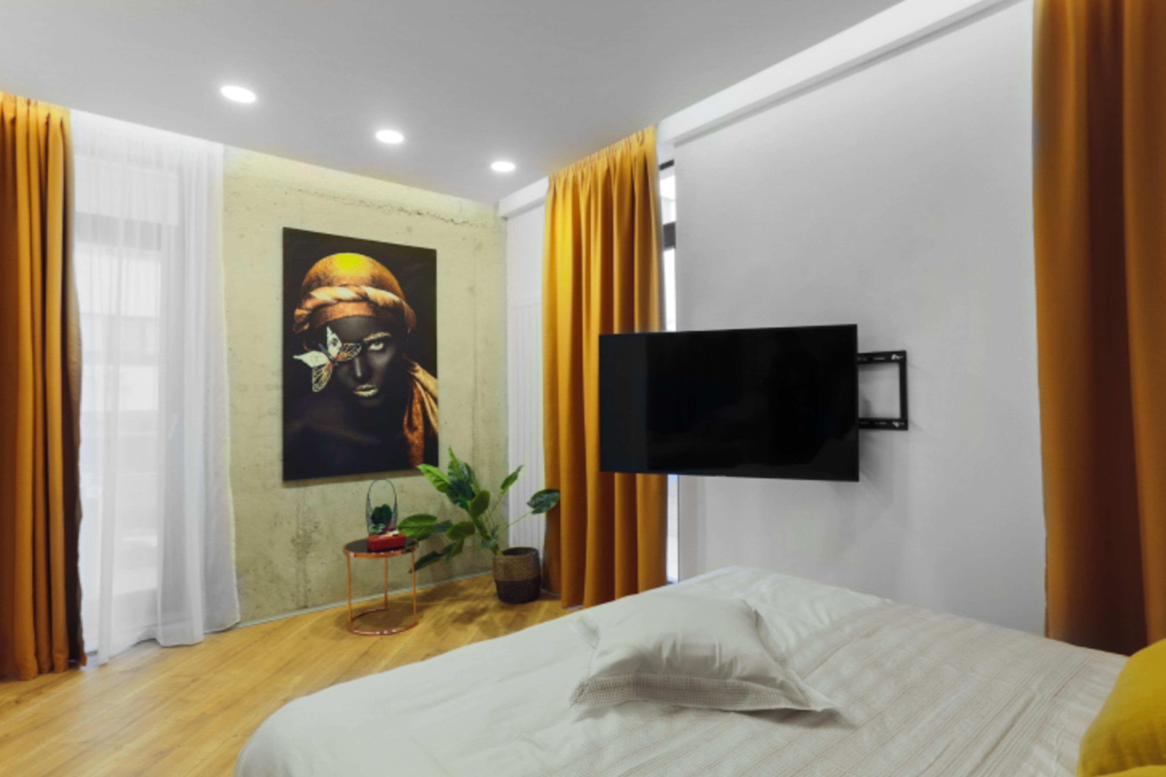 Une chambre à coucher moderne avec un lit, un téléviseur à écran plat fixé au mur et un tableau accroché au mur.
