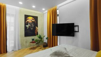 Une chambre à coucher moderne avec un lit, un téléviseur à écran plat fixé au mur et un tableau accroché au mur.
