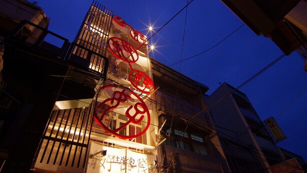 Um edifício com letreiros iluminados, com desenhos circulares vermelhos e caracteres chineses.