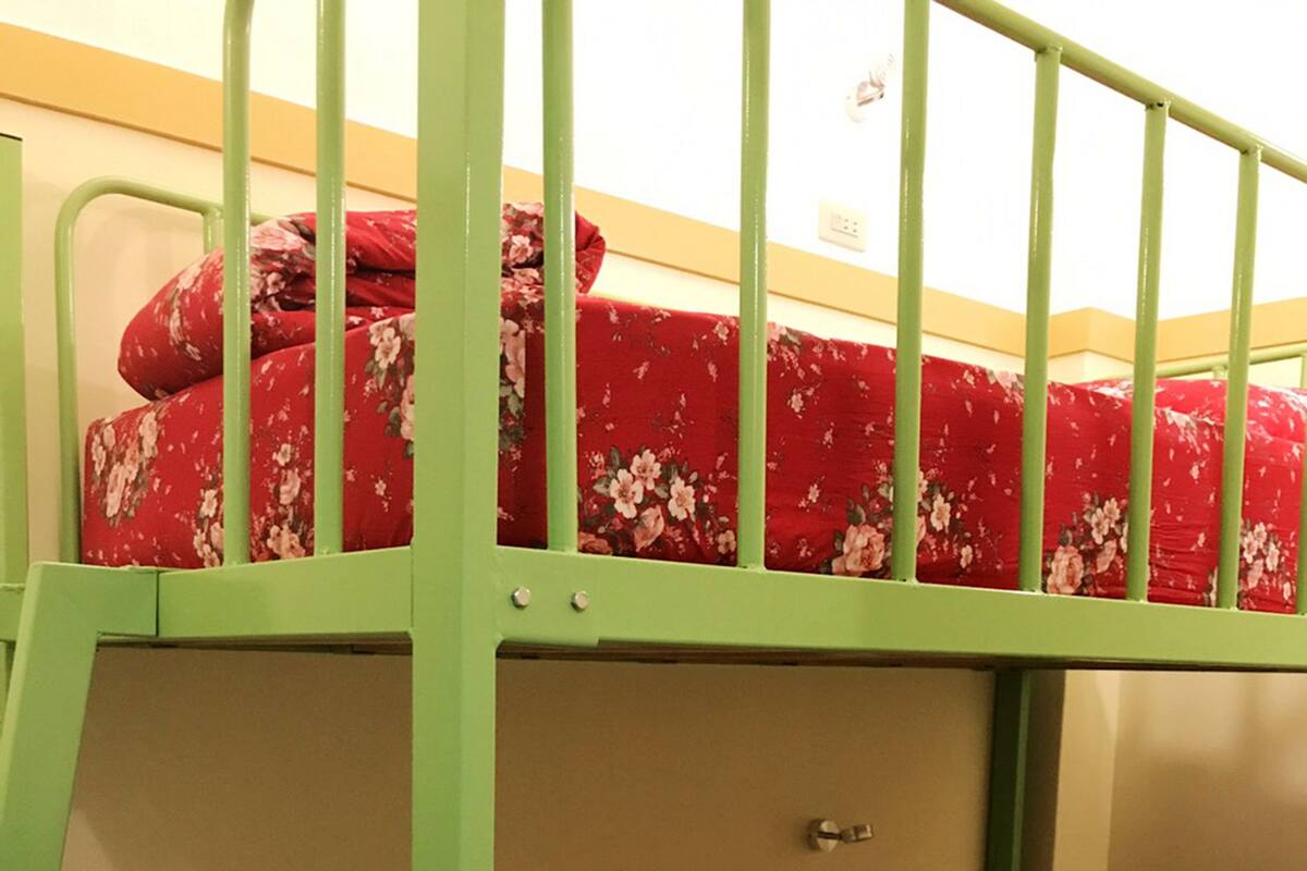 Uma cama beliche com roupa de cama floral e grades de metal verde.