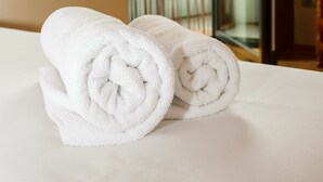 Ein ordentlich gemachtes Bett mit zwei zusammengerollten weißen Handtüchern.