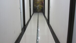 Un pasillo con puertas a ambos lados, suelo de baldosas y un mural en la pared de fondo.