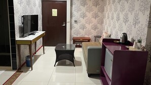 Un espacio habitable compacto con televisor, una mesita, sofá y una kitchenette.