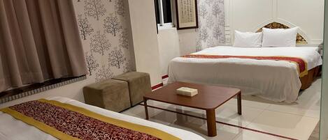 A hotel room with two beds, a small table, a sofa, and a decorative wall.