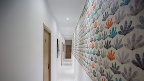 Un pasillo con pared estampada, puertas de madera y cuadros en la pared.