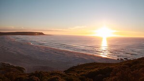 A coastal landscape with a beach and ocean during sunset. - Sunset Cottage- Noordhoek (Cape Town)