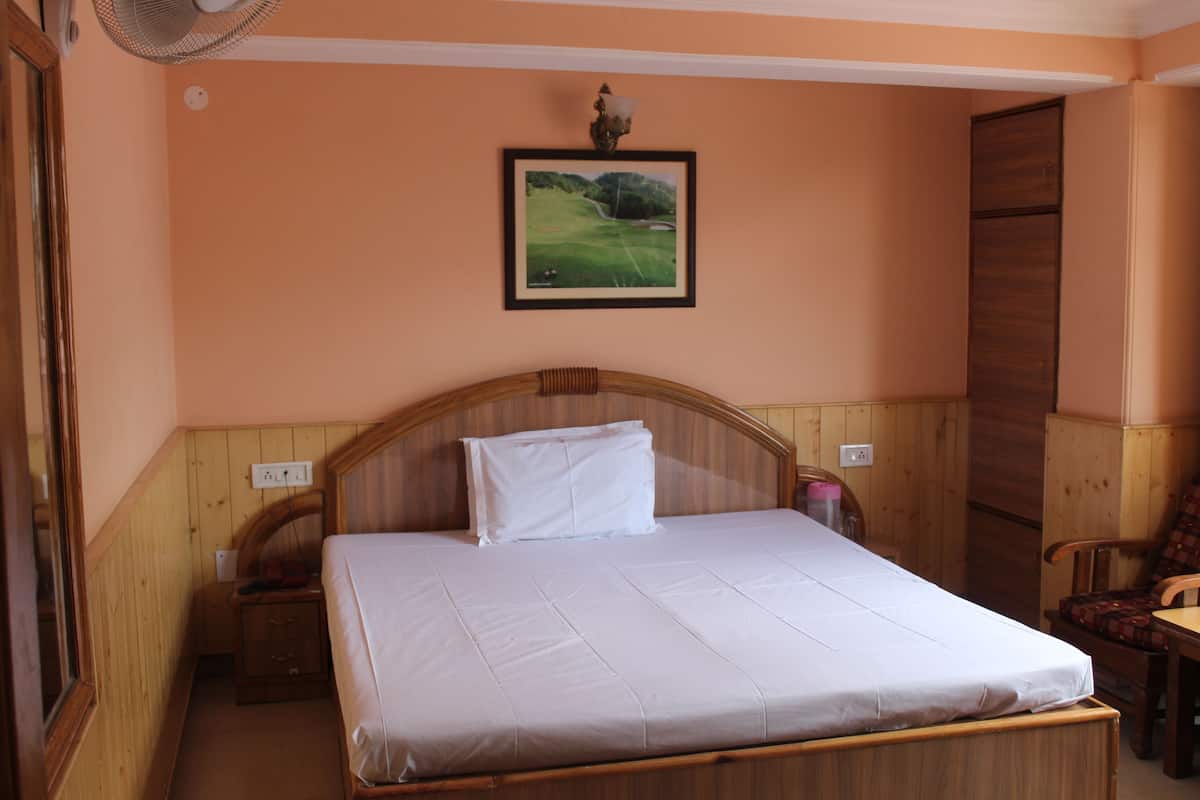 A bedroom with a wooden headboard, a single bed, a nightstand, a chair, and a framed picture on the wall.