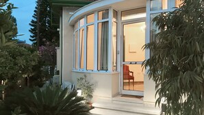 A modern house with a curved facade, large windows, and a visible interior with a chair and a table. - Avgi's Home (Limassol)