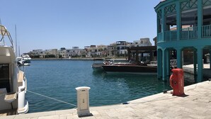 A marina with boats docked, a lifebuoy, and a building with a balcony. - Avgi's Home (Limassol)