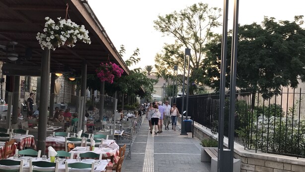 An outdoor dining area with tables and chairs, a covered walkway, and a fence. - Avgi's Home (Limassol)
