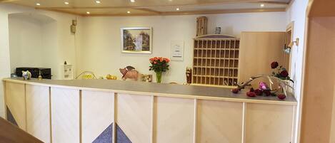 Un mostrador de recepción con detalles de madera, un perchero para llaves en la pared y un cuadro enmarcado encima.