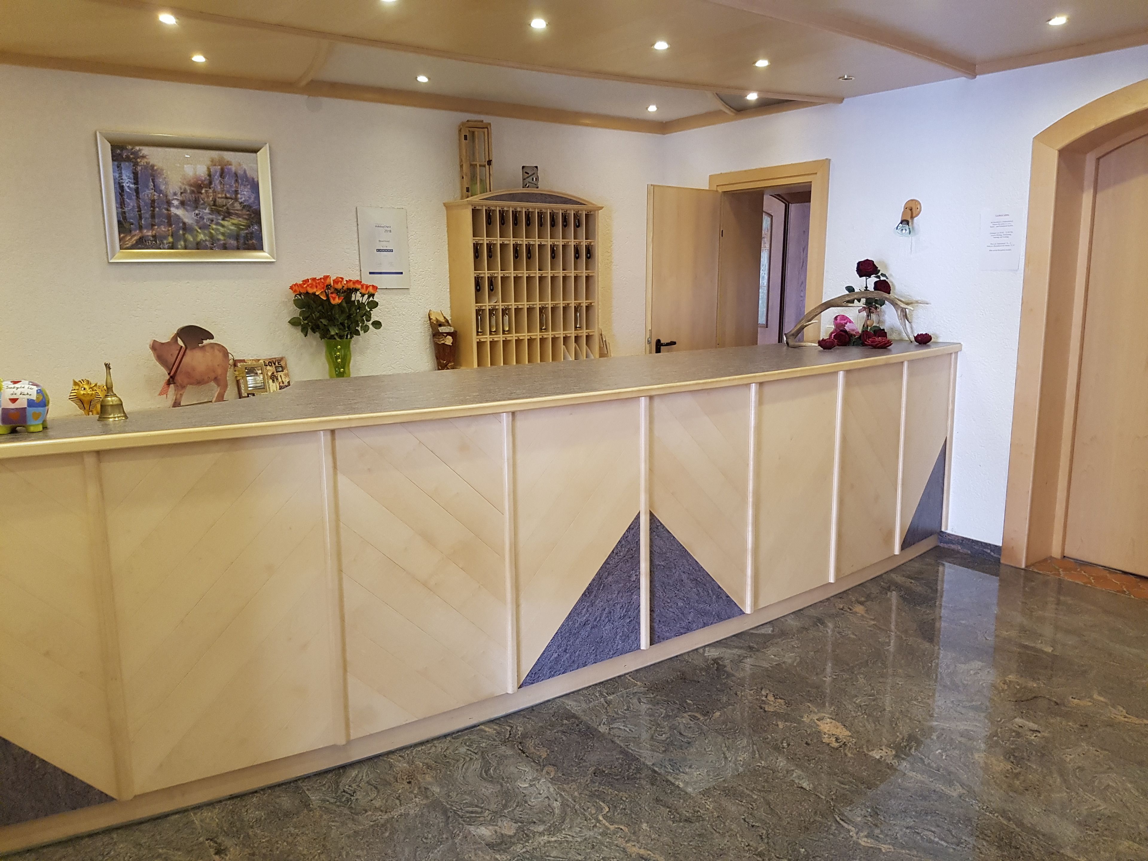 A reception desk with a marble floor, a framed painting, and a wooden cabinet with hooks.