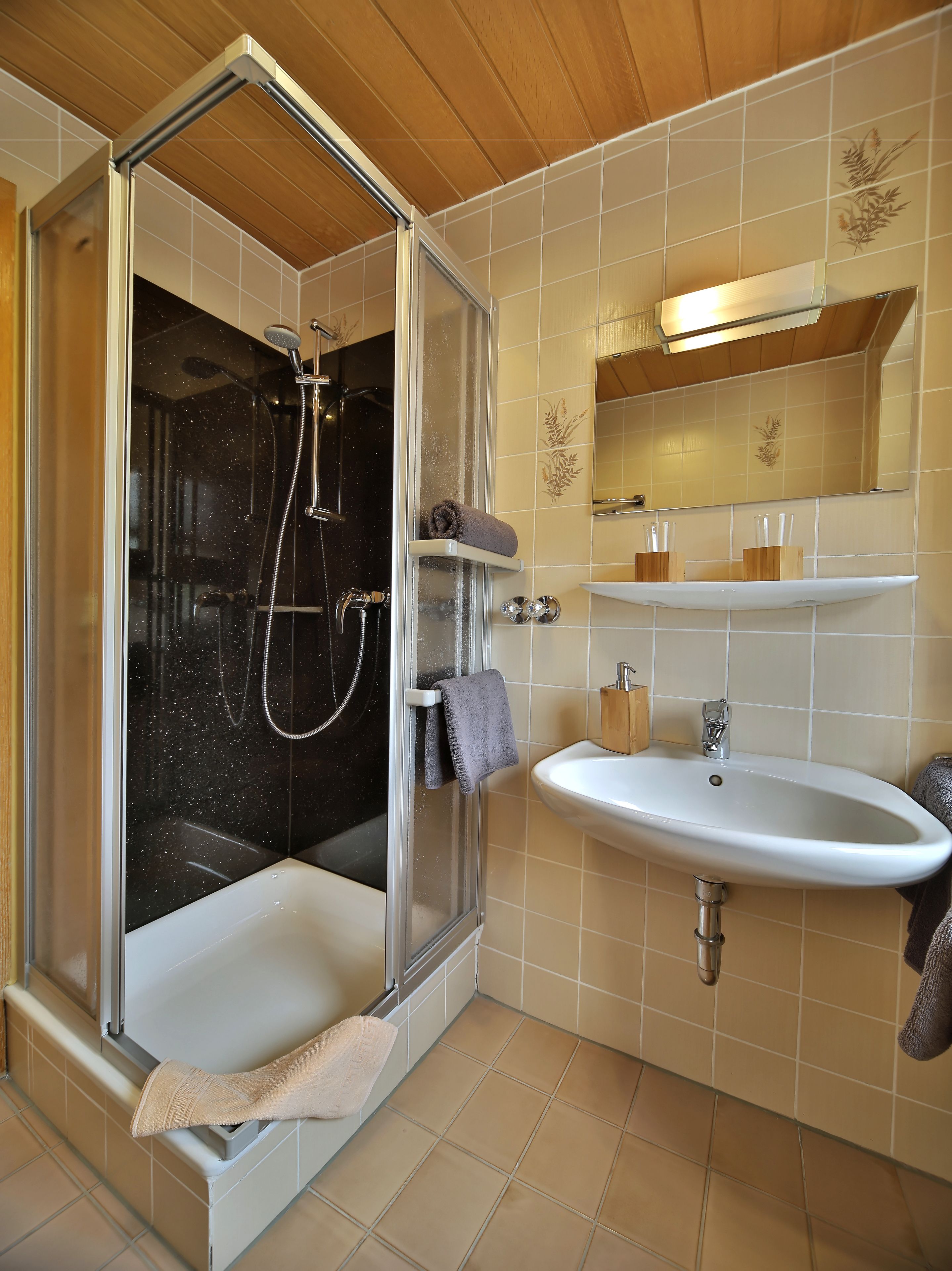A bathroom with a glass-enclosed shower, a white sink, and a mirror above it.
