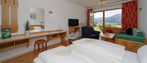 Ein Hotelzimmer mit einem großen Bett, einem Schreibtisch mit Computer, einem Fernseher und Blick ins Freie.