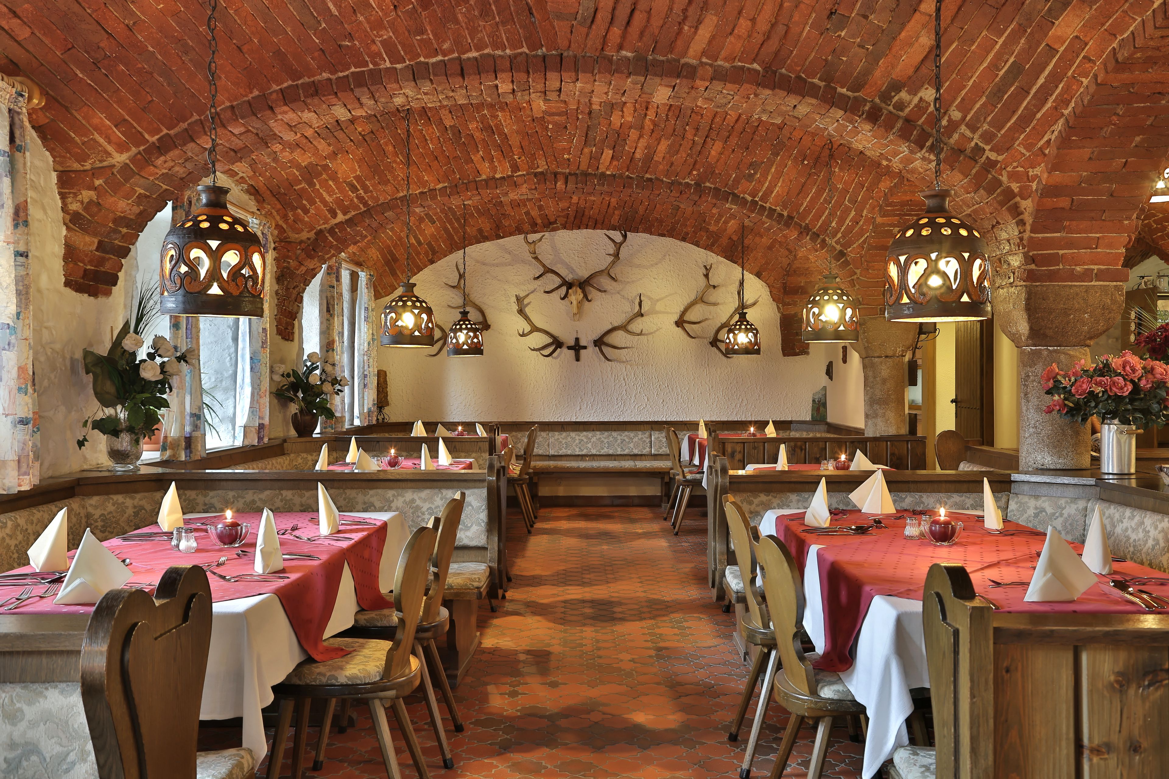 A restaurant with brick arches, wooden tables, and candle-lit chandeliers.
